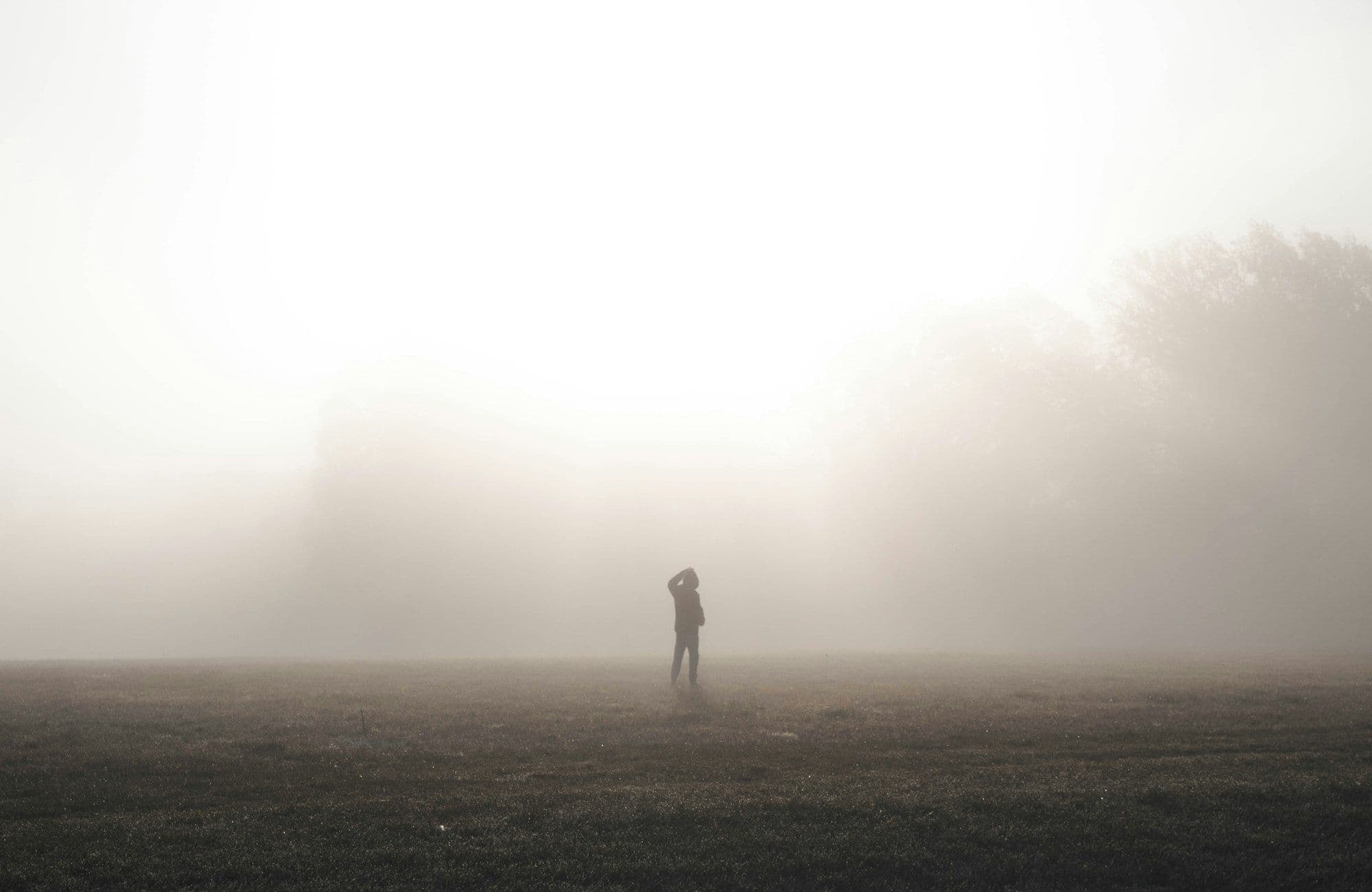 Photograph of a lone figure standing in thick morning fog