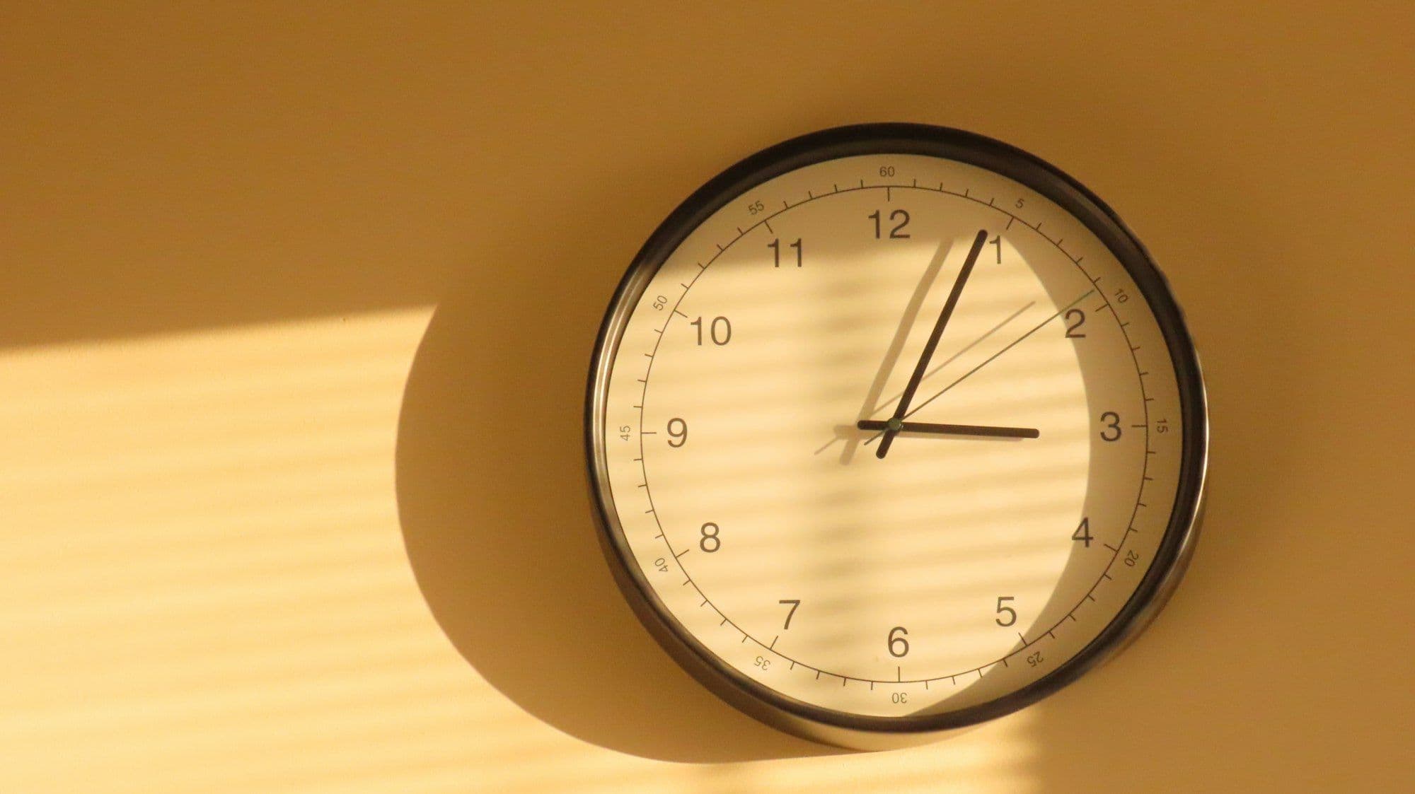 Photograph of a wall clock showing three o'clock in soft afternoon light