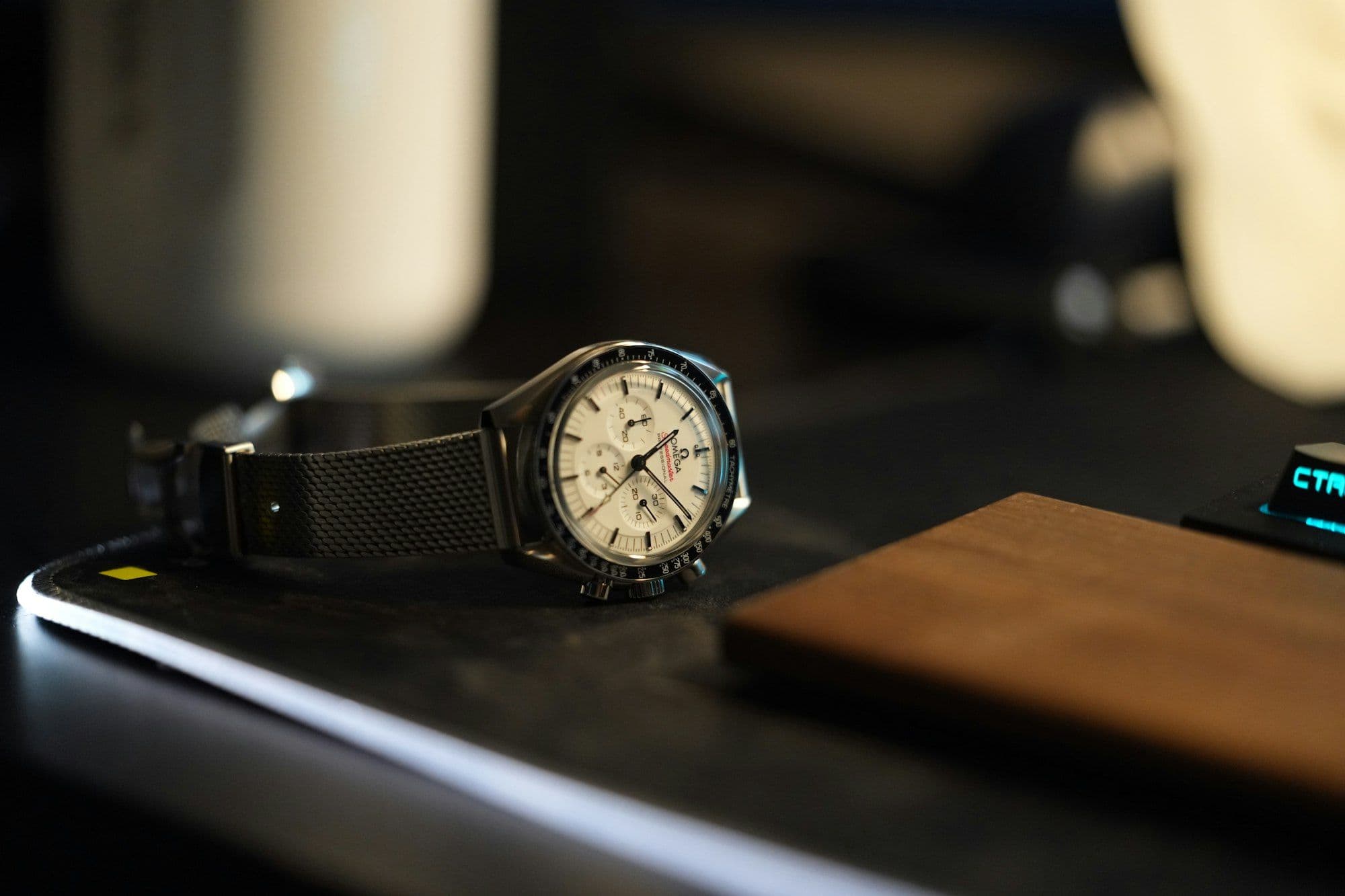 A chronograph wristwatch resting on a dark surface, its dial catching the light.