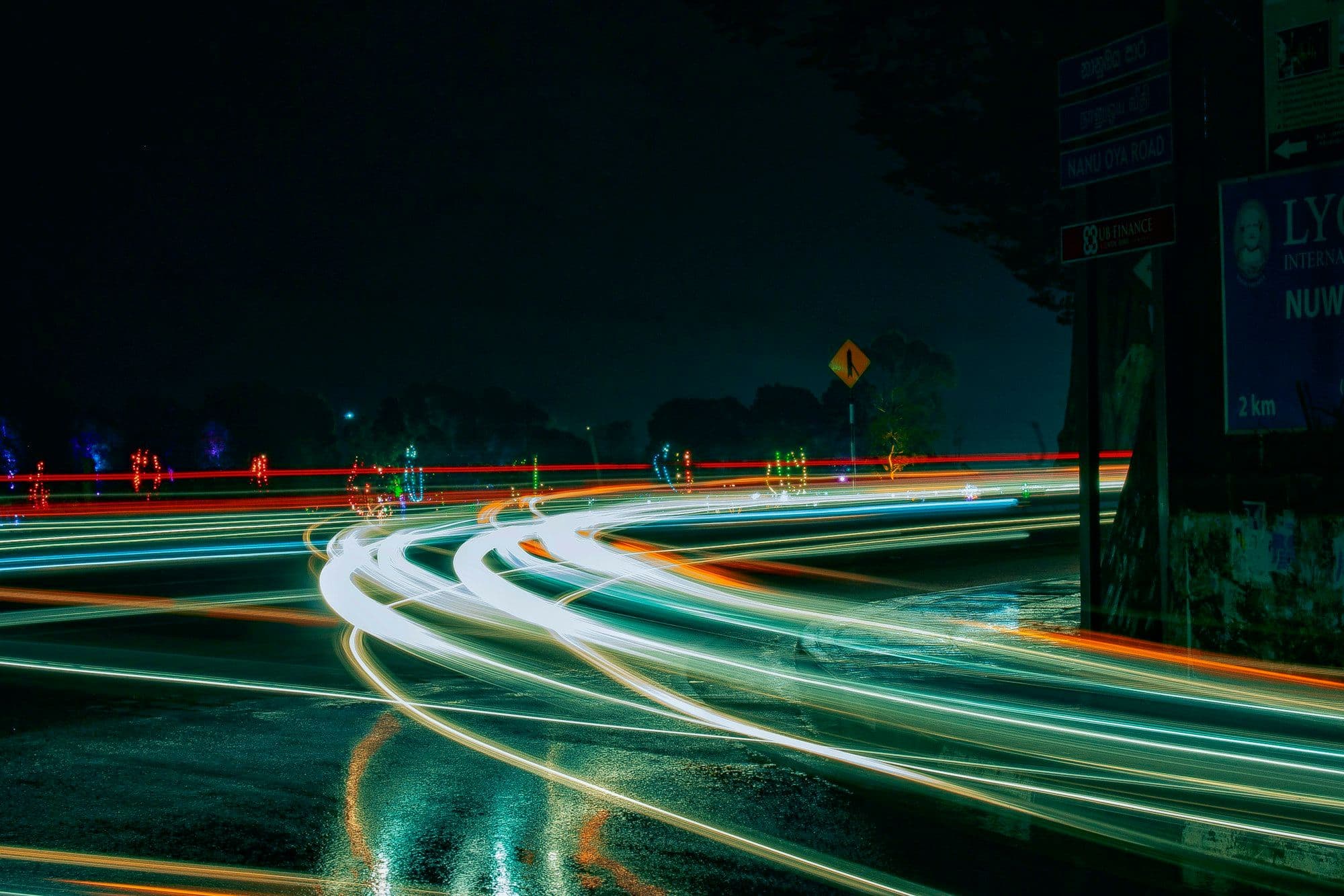 Photograph of curving light trails on a wet road at night